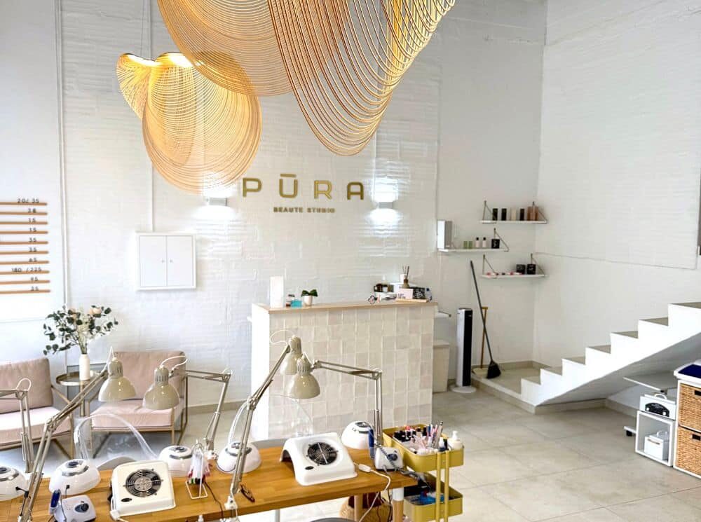 Pura Beaute logo behind the reception desk. All white modern interior